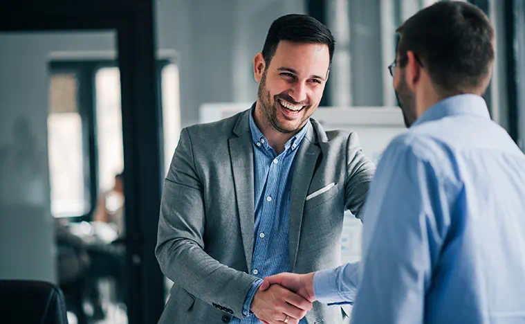 Two business men shaking hands in a modern office.