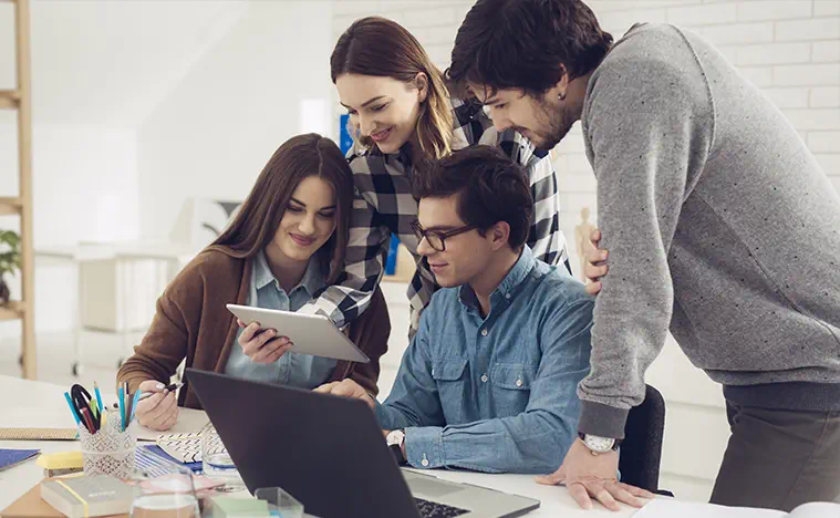 A group of young professionals looking at a laptop together.