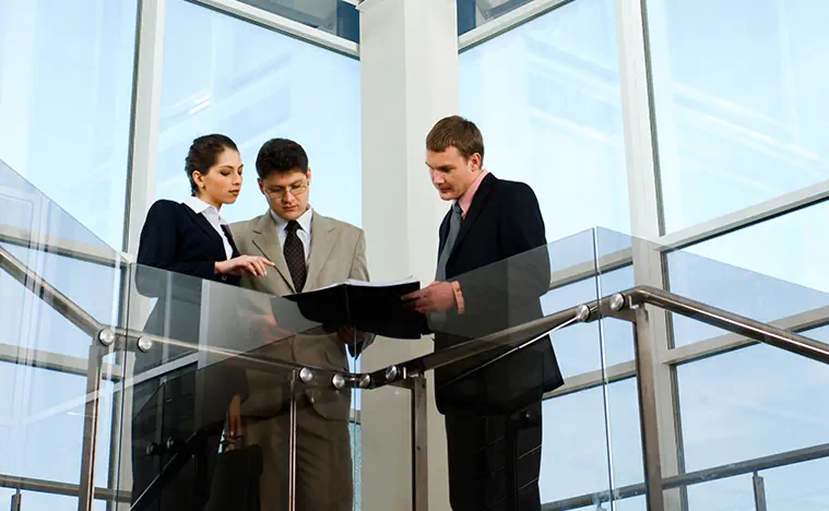An agent goes over a listing with clients in a glass lined office building.